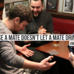 A mate has spilt a pint of beer to prevent drink driving. Text on screen reads: 'Because a mate doesn't let a mate drink drive. #MatesMatter'