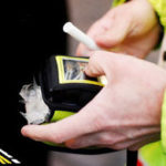 Hands of a police officer holding a breathalyser kit.