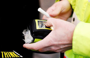 Hands of a police officer holding a breathalyser kit.