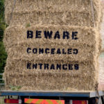 Lorry carrying bales of hay with 'Beware concealed entrances' on it