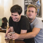 friend stopping other friend from drinking their pint
