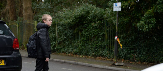 child crossing road in between two parked cars