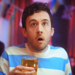 Man holding pint looking shocked